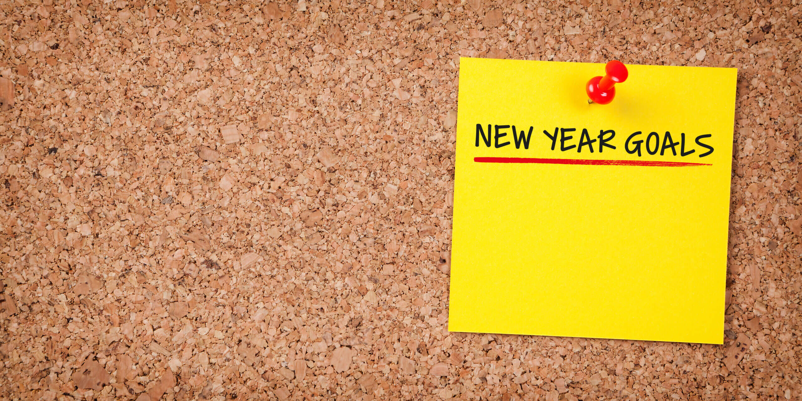 post-it note on a corkboard that reads new year goals