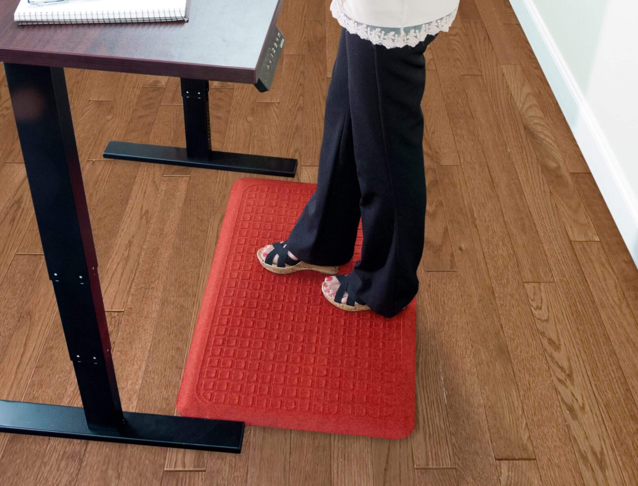 Woman standing on an anti-fatigue mat at her desk