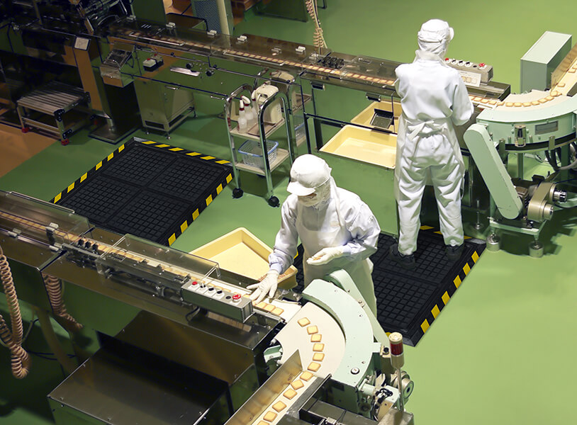 factory workers at work standing on anti-fatigue mats